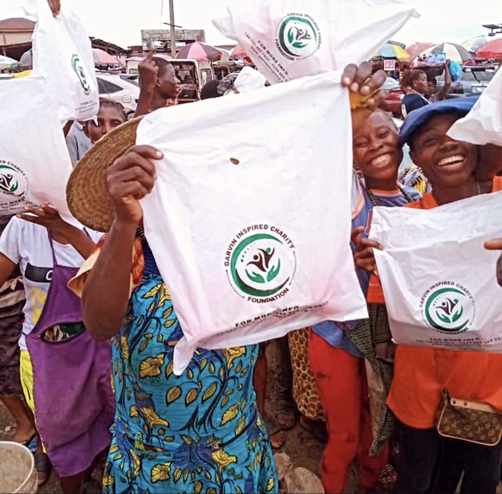 Community members holding Garvin Inspired Charity Foundation relief bags during a market outreach