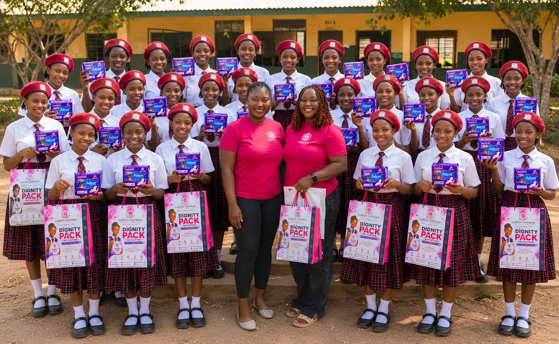 Dozens of schoolgirls with Garvin Inspired Charity Foundation volunteers holding Dignity Pack kits