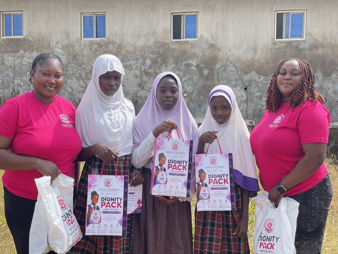 Garvin Inspired Charity Foundation volunteers with schoolgirls holding Dignity Pack bags